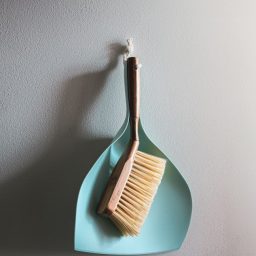 A dust brush and dust pan on a wall.
