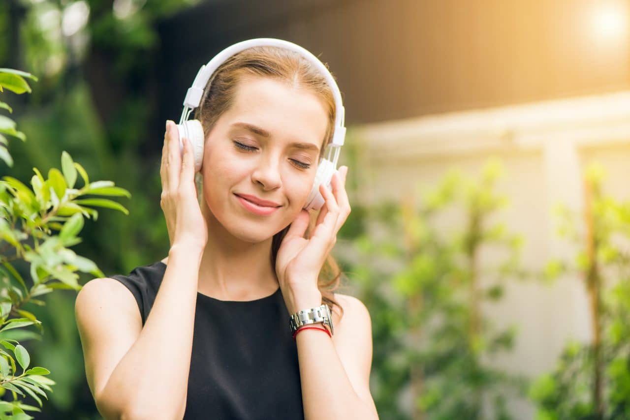 Woman wearing headphones and happily listening to music.