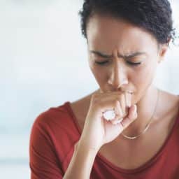 Adult woman coughing in her office.